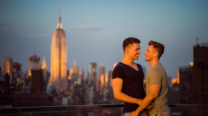 Gay couple embracing on a Manhattan rooftop with the New York skyline at sunset.