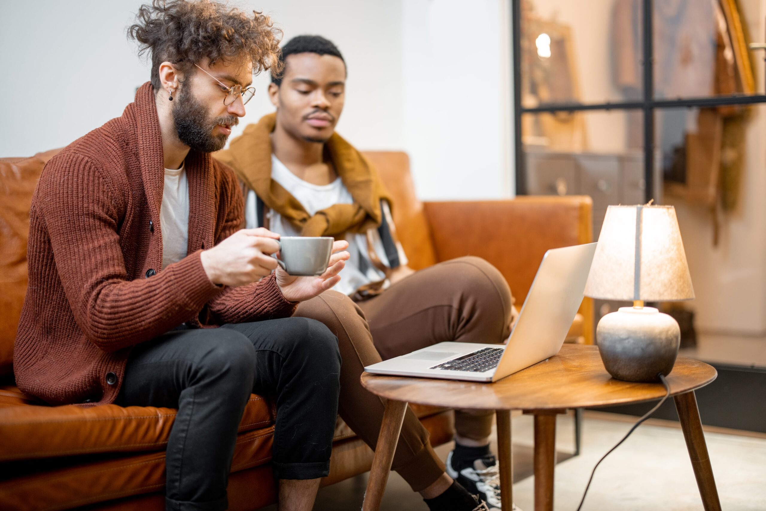 Two men displaying emotional vulnerability during online gay couples therapy focusing on conflict resolution skills after betrayal.